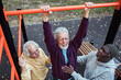© Marko Geber - Senior men exercising together on pull-up bar in outdoor park fitness area
