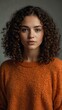 © claudunia - Woman with curly hair in an orange sweater.