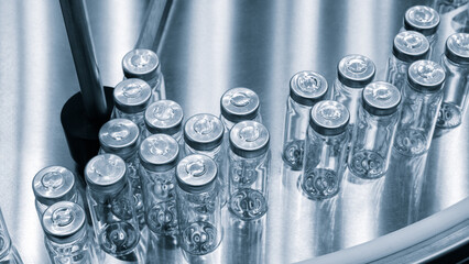 Poster - A row o clear bottles . The bottles are lined up on a table, pharmaceutical production of drugs and vaccines
