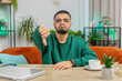 © Andrii Iemelianenko - Dislike. Upset unhappy Indian man showing thumbs down sign gesture, expressing discontent, disapproval dissatisfied bad work at home office indoors. Displeased Arabian young guy in room at table