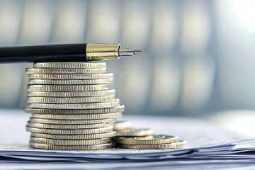 Poster - Stacked coins with pen on top, symbolizing finance and investment. image captures essence of saving and financial planning, showcasing thoughtful approach to money management