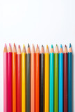 Colorful group of pencils and crayons arranged in a row on a white background