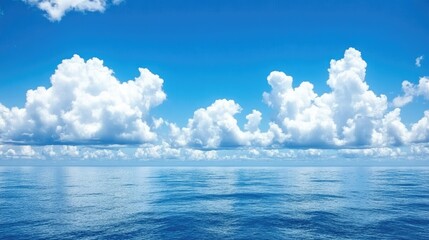Wall Mural - clear blue sky with white fluffy clouds above a calm ocean, a peaceful seascape