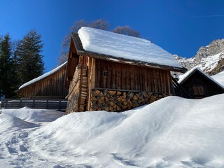 Old traditional swiss rural architecture and alpine livestock farms in the winter ambience over the Lake Walen or Lake Walenstadt (Walensee) and in Swiss Alps, Walenstadtberg - Switzerland (Schweiz)