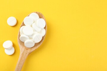 Wall Mural - Antibiotic pills in spoon on yellow background, top view. Space for text