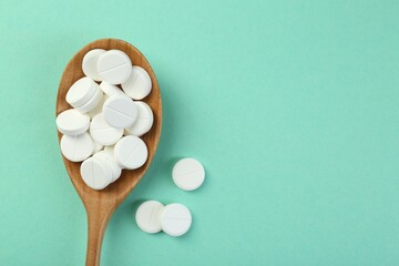 Wall Mural - Antibiotic pills in spoon on turquoise background, top view. Space for text