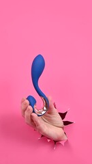 Wall Mural - Hand with blue vibrator sticking out through pink paper background. 