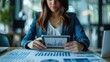 © Fana Art - Businesswoman reviewing financial data on tablet.