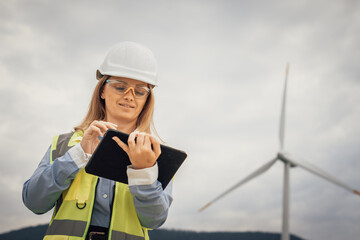 Poster - A dedicated female engineer is at a wind farm, using a tablet equipped with advanced technology to conduct thorough data analysis, showcasing innovation and a strong commitment to sustainability