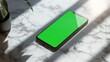 © Aisha - A smartphone with a green screen resting on a marble surface with reflections of nearby objects