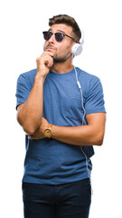 Canvas Print - Young handsome man wearing headphones listening to music over isolated background with hand on chin thinking about question, pensive expression. Smiling with thoughtful face. Doubt concept.