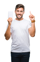 Canvas Print - Young handsome man holding notebook over isolated background surprised with an idea or question pointing finger with happy face, number one