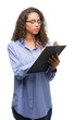 © Krakenimages.com - Young hispanic business woman holding clipboard with a confident expression on smart face thinking serious