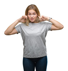 Wall Mural - Young caucasian woman over isolated background covering ears with fingers with annoyed expression for the noise of loud music. Deaf concept.