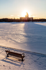 Wall Mural - a bench sits in the snow next to a body of water