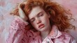 © Viktoriia - Woman with red hair in pink jacket lounging on a soft surface in a bright setting