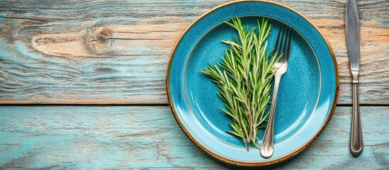 Poster - Rustic table setup with rosemary on blue plate and cutlery for a romantic dining experience top view on light wooden background