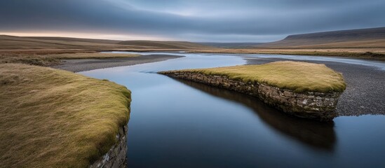 Poster - Winter landscape with serene river flowing through dramatic terrain under overcast sky during early morning light