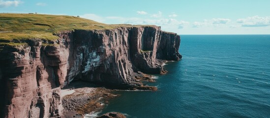 Poster - Majestic coastal cliffs rising steeply above the serene blue sea under a bright summer sky in a picturesque natural landscape