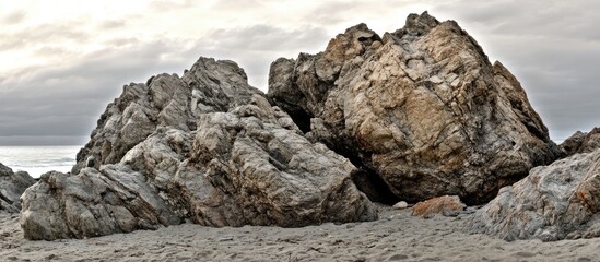 Aufkleber - Coastal landscape featuring rugged rocks on a sandy beach with a dramatic overcast sky in the background