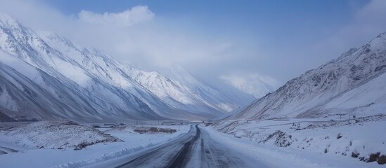 Aufkleber - Snowy mountain roads with dramatic landscapes under a blue winter sky showcasing the beauty and serenity of winter travel.