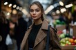 © Babb - A woman wearing a brown coat stands in front of a fruit stand