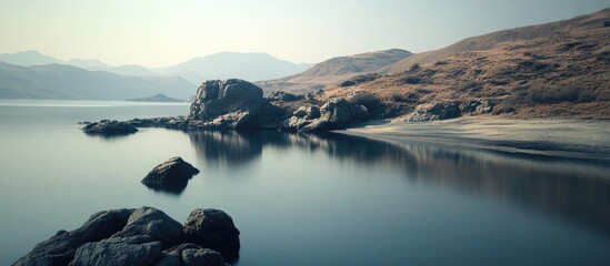 Poster - Tranquil lakeside landscape with gentle blue waters, rocky shorelines, and serene mountains in the background under a clear sky.