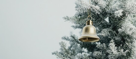 Poster - Golden bell ornament hanging from a Christmas tree with frosted branches against a soft white background festive holiday decor concept