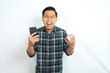 © M Alfan Setyawan - furious asian man shouting while holding cellphone and raising his hand show angry face isolated on white background
