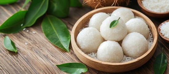 Wall Mural - Coconut Dumplings Made with Sticky Rice and Fresh Leaves in a Rustic Wooden Bowl