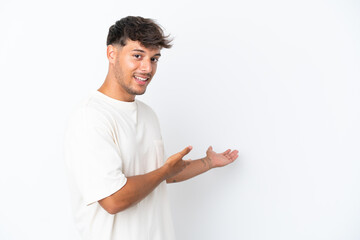 Sticker - Young caucasian handsome man isolated on white background extending hands to the side for inviting to come