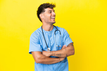 Sticker - Young surgeon doctor man isolated on yellow background happy and smiling