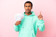© luismolinero - Young man taking a lot of money over isolated pink background thinking an idea pointing the finger up