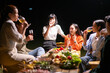 © Wasana - A group of people are sitting around a table with food and drinks