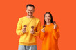 © Pixel-Shot - Young couple with tasty cookies on orange background