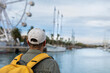 © Carlos - Man with yellow backpack on the promenade of the port of Barcelona