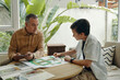 © DragonImages - Grandfather helping to make family tree to his grandson while they sitting at table in the room