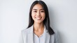 © Sulton - A beautiful Japanese woman in her early to mid-20s with straight hair, smiling and looking directly at the camera against a white background. She is wearing business casual attire of light gray color,