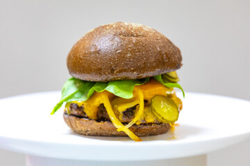 Wall Mural - Traditional rustic burger sandwich with cheddar cheese, vegetables and Australian bread in creative photography and cozy village setting