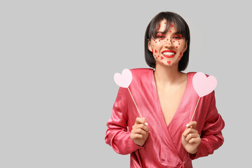 Poster - Beautiful young young woman with creative makeup for Valentines Day and hearts on grey background