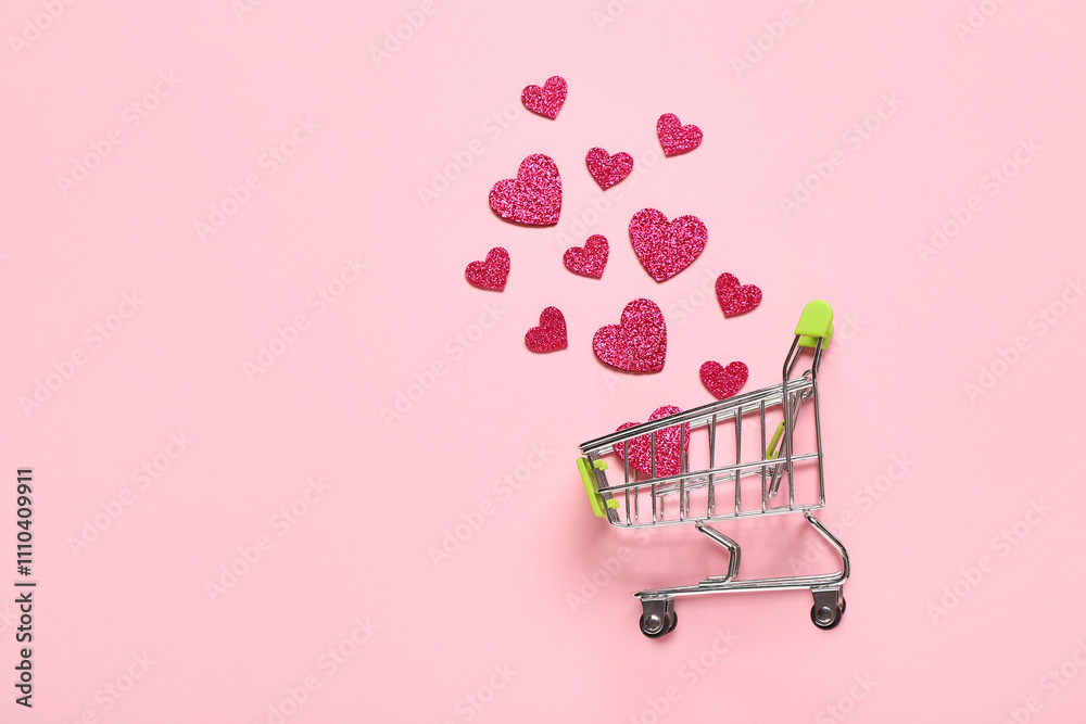 Small shopping cart with paper hearts on pink background. Valentine's Day celebration