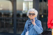 © Austockphoto - elderly lady wearing sunglasses with denim sitting with hand to face