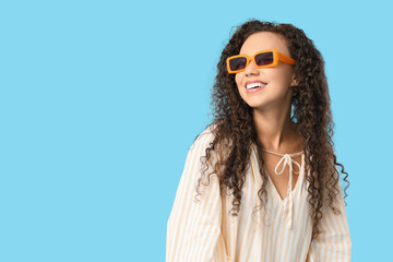 Poster - Beautiful African-American woman with sunglasses on blue background