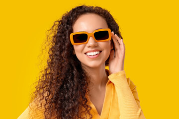 Poster - Beautiful African-American woman with sunglasses on yellow background