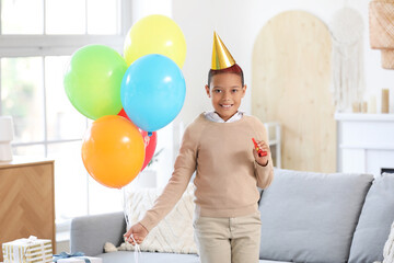 Wall Mural - Cute little African-American boy in party hat with whistle and air balloons celebrating birthday in living room