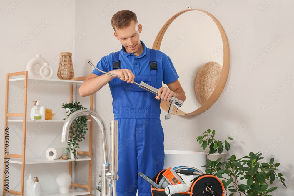 Male plumber fixing sink faucet in bathroom