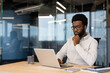 © Liubomir - African American businessman thinking laptop work. Capturing thoughtful expression, business attire, office ambiance. Represents focus, technology usage, corporate environment, decision making.