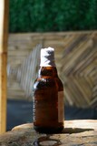 Piwo w małej butelce postawione na stole. Schłodzone piwo w niewielkiej brązowej butelce. Otwarty napój alkoholowy na pierwszym planie.