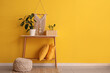 © Pixel-Shot - Table with plants, pillows and pouf near yellow wall in room