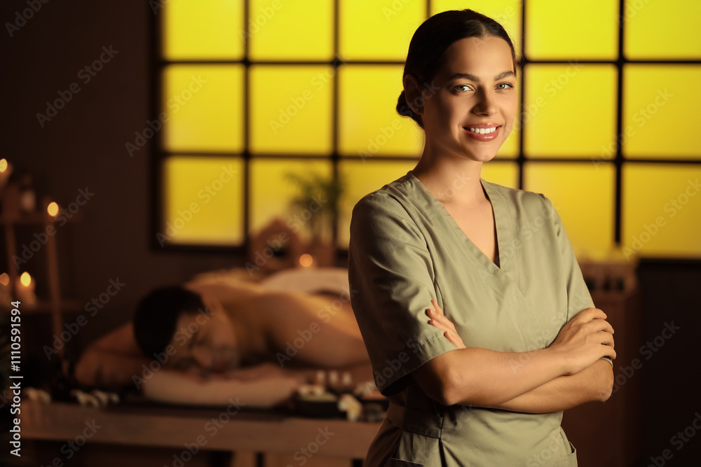 Female massage therapist smiling in dark spa salon